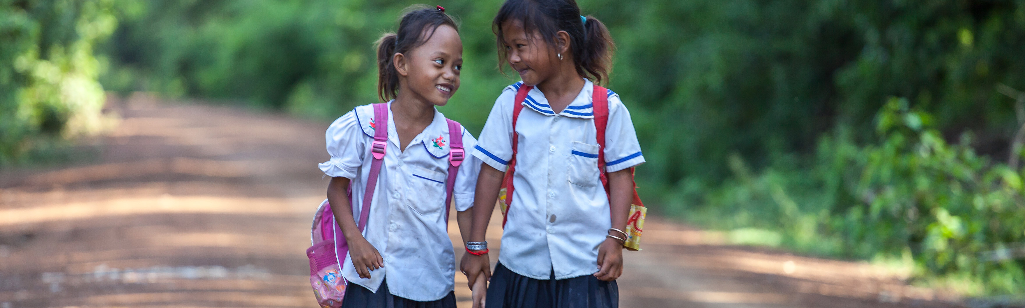 Cambodia, Kampong Champ, Channa, amputated and fitted with a prosthesis by HI, here on her way to school with a friend.
