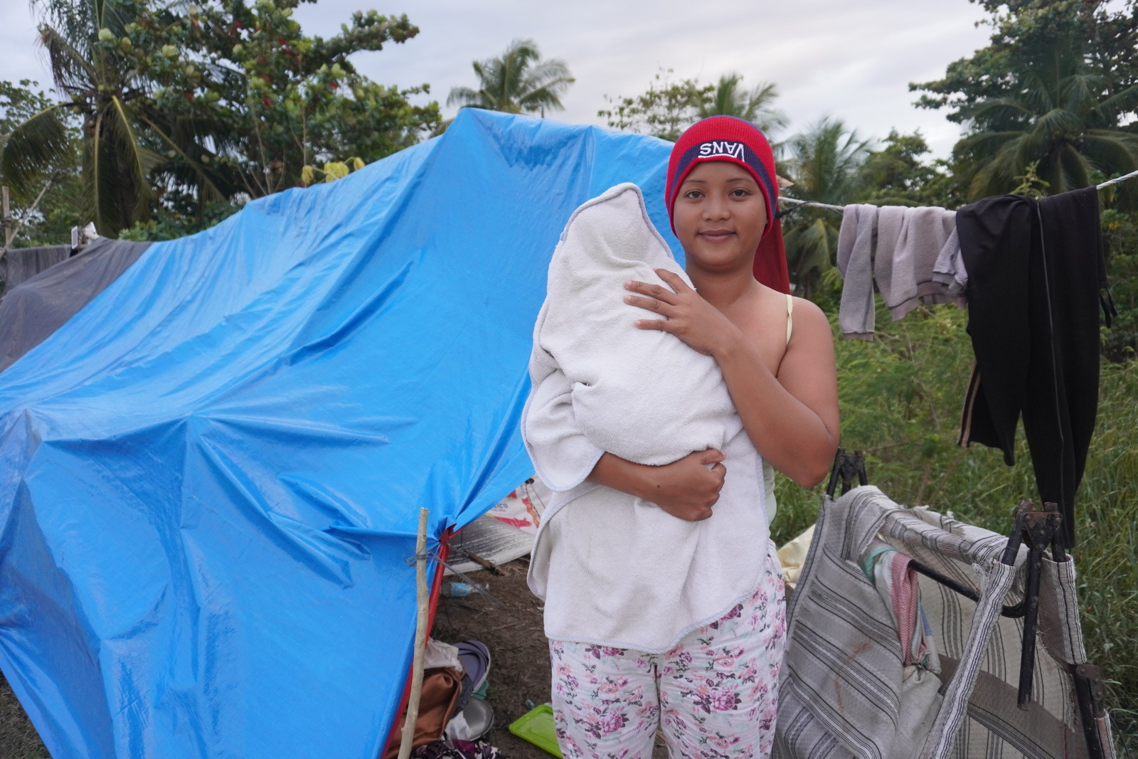 Charlyn et son bébé devant leur abri, victime des inondations, dans la ville de Carmen, Davao del Norte, aux Philippines. © Maria Clarissa Manalastas / HI