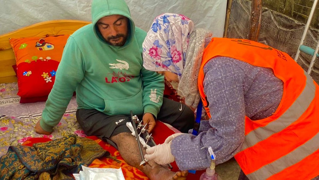 Wala en train de nettoyer la blessure d'un patient dans un camp de déplacés à Rafah. ; }}